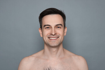 Smiling man after shaving on grey background