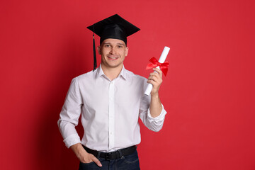 Happy student with diploma after graduation on red background