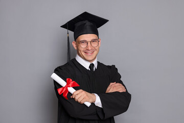 Happy student with diploma after graduation on grey background