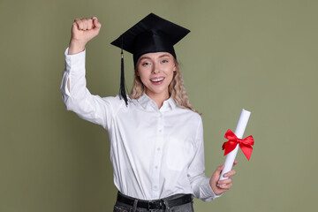 Happy student with diploma after graduation on green background