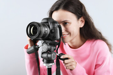 Woman with professional video camera on light grey background