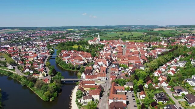 Luftaufnahme von Donauw&ouml;rth mit roten D&auml;chern, historischen Geb&auml;uden und einem markanten Turm, eingebettet in eine gr&uuml;ne Landschaft. Die Stadt bietet eine charmante Kulisse. 