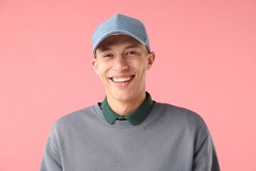 Young man in stylish baseball hat on pink background