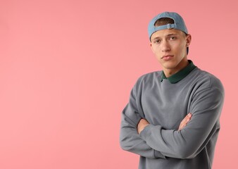 Young man in stylish baseball hat on pink background, space for text