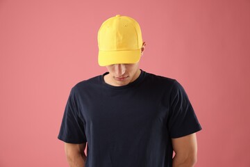 Young man in stylish baseball hat on pink background