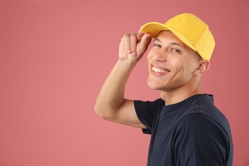 Young man in stylish baseball hat on pink background, space for text