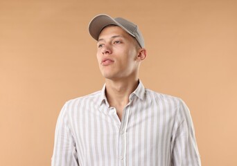 Young man in stylish baseball hat on beige background