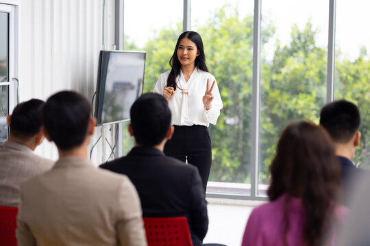 Public speaking training in seminar : Asian business female leader in seminar, speaking on business training with group of diverse people company employees in meeting room - Powered by Adobe