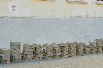 Stacked paving bricks against an old wall during foundation renovation and waterproofing work on an urban construction site