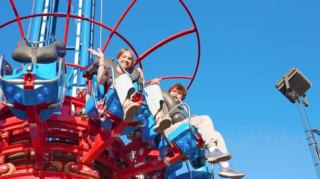 A young guy and his girlfriend ride a free fall attraction in an amusement park