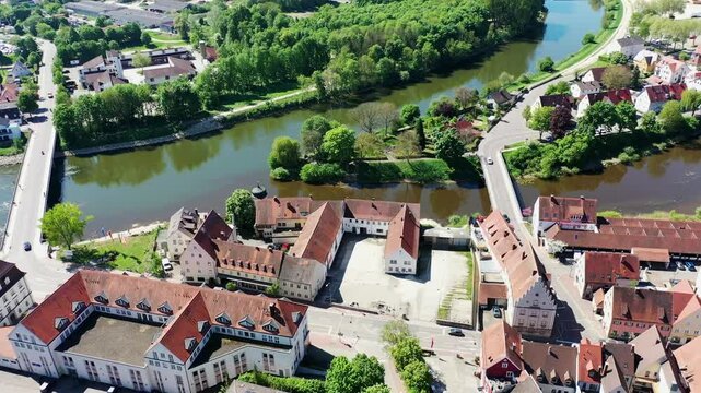 Luftaufnahme von Donauw&ouml;rth mit roten D&auml;chern, historischen Geb&auml;uden und einem markanten Turm, eingebettet in eine gr&uuml;ne Landschaft. Die Stadt bietet eine charmante Kulisse. 