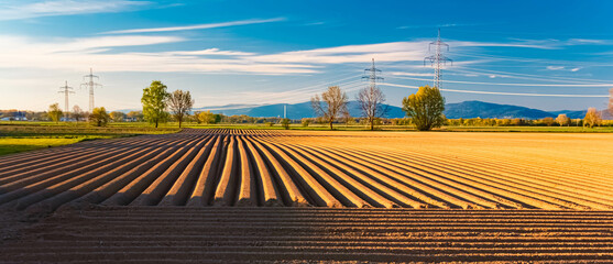 Spring landscape with shade producing furrows and the Bavarian Forest in the background near...