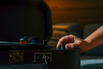 Close-up of hand adjusting volume knob on turntable while vinyl record plays, creating warm...