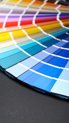 A fan of colorful paint swatches on a dark surface