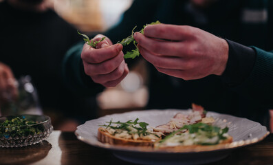A close-up view of a person adding fresh toppings to sandwiches in a relaxed atmosphere, showcasing...