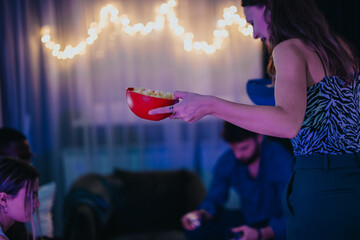 A group of friends gathers for a warm celebration enjoying snacks in a cozy living space. The stringed lights create a welcoming atmosphere, enhancing the joy of bonding and togetherness.