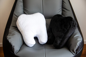 A stylish arrangement of white and black dental-themed pillows placed on a gray chair in a...