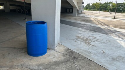 Blue Plastic Barrel Near Concrete Pillar in Urban Parking Area