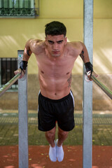 Young athlete performing calisthenics dips on parallel bars in urban setting