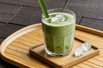 Fresh green smoothie served in a glass on a wooden tray, perfect for a healthy breakfast or snack