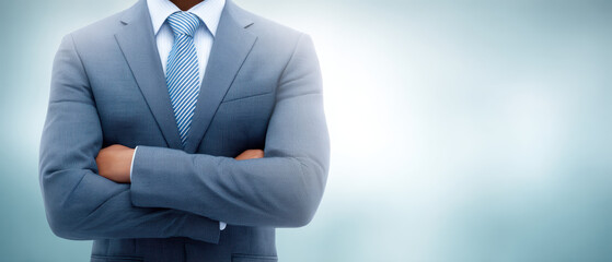 Confident businessman in gray suit with arms crossed against blurred background