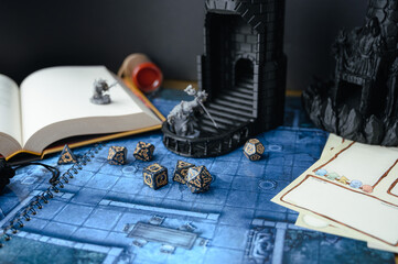 Top-down view of a tabletop RPG setup with dice, miniatures, character sheets, a dice tower, and a...
