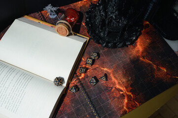 Top-down view of a tabletop RPG setup with dice, miniatures, character sheets, a dice tower, and a...