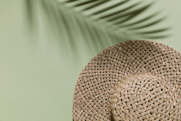 Summer flat lay with straw hat on green background with palm leaf shadow, sun and sunlight. Vacation, holiday, summer creative minimal concept, copy space, banner.