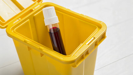 Biohazard waste container with medical blood sample tube for safe disposal in healthcare