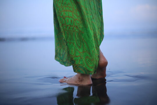 Woman Barefoot on Wet Black Sand Beach in Green Silk Dress
