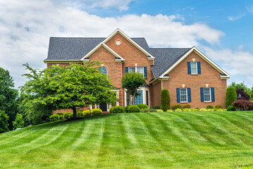 large traditional red brick colonial house on a green lawn in Virginia.
