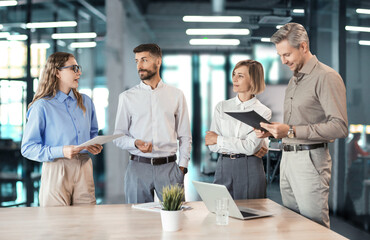 Three business people discussing work together using a tablet in a modern office