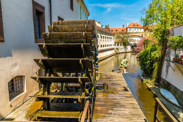 A view past a water wheel on a tributary to the Vltava river in Prague in springtime