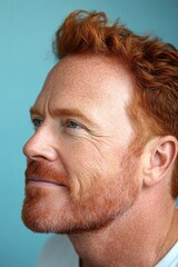 Fototapeta premium Elegant men's slick back with fade haircut - midlife white man with red hair. Blue solid background. Visual idea art of style for aging men. A man with timeless elegance and a natural smile.