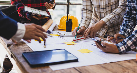 Team of architects and engineers working on construction project. Architect and engineer are using pencil, ruler on table with blueprint to discuss construction project. Construction design planning.
