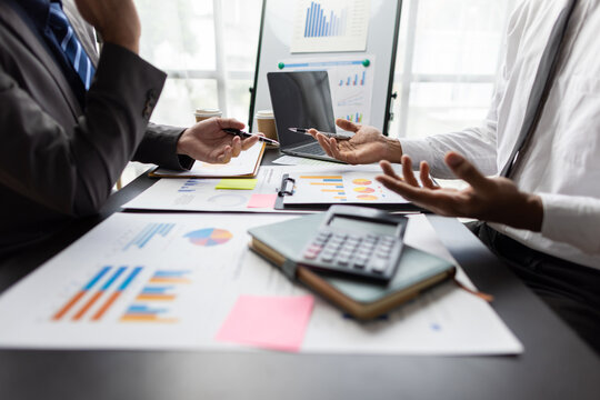 Financial advisor analyzing financial report and chart at meeting. Businessman using calculator and pointing at financial document, discussing about marketing strategy for investing in a new project.