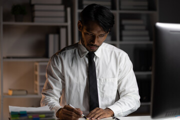 Focused businessman working overtime in office at night. Businessman is concentrating on his work...