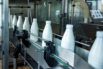 White plastic milk bottles on the conveyor on a modern dairy plant