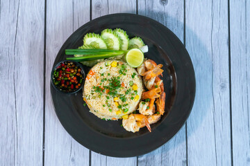 Fried rice with shrimp on the white dish on wooden table
