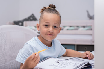 Junge mit Farbstiften malt im Kinderzimmer