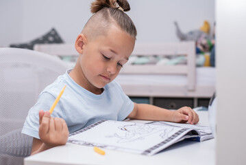 Junge mit Farbstiften malt im Kinderzimmer