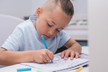 Junge mit Farbstiften malt im Kinderzimmer