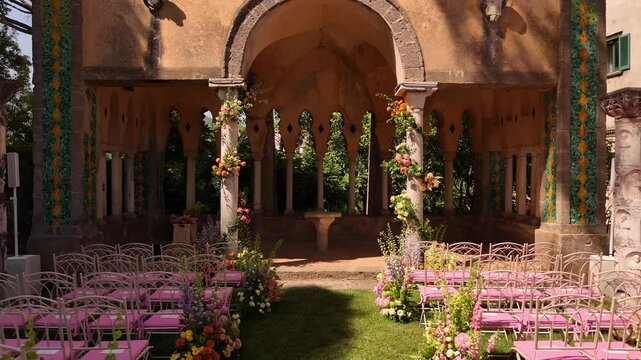 Drone view of Amalfi Coast luxury wedding details: pink chairs, fresh florals, elegant setup at Villa Cimbrone, Ravello. Perfect destination wedding planning vibes see view