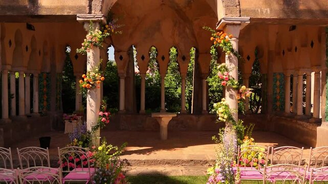 Drone view of Amalfi Coast luxury wedding details: pink chairs, fresh florals, elegant setup at Villa Cimbrone, Ravello. Perfect destination wedding planning vibes see view