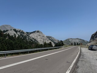 road in the mountains Empty mountain road winding through rocky terrain with clear skies overhead,...