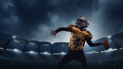 Quarterback in golden jersey prepares to throw pass in illuminated stadium during night match with...
