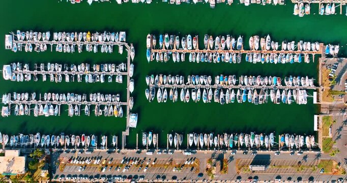 Rows of modern boats at the berths of the yacht club. Top view on the water vehicles near the shore of Honolulu, Hawaii, USA.