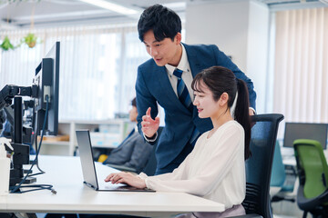 先輩に仕事を教えてもらう若い女性の会社員