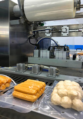 Machines are wrapping processed fresh food products meatball sausages . food production lines on conveyor belts, food production industry
