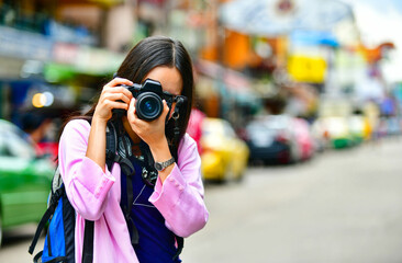 Asian women taking photo in Khao San road during vacations in Bangkok, Thailand
